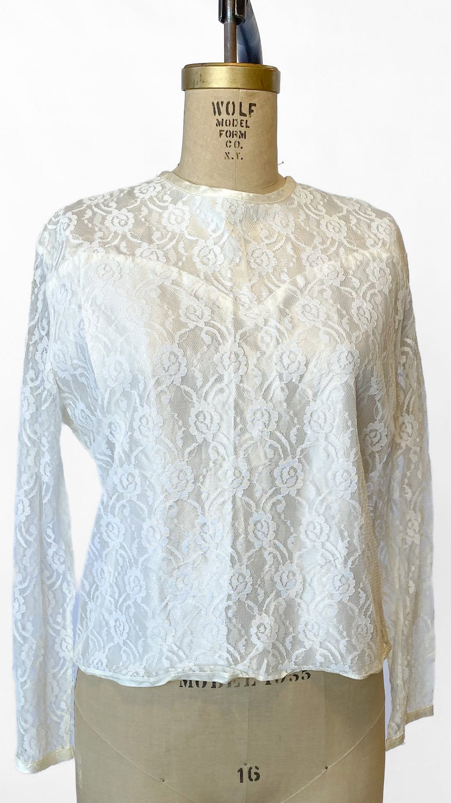 White lace blouse on a mannequin with a plain background