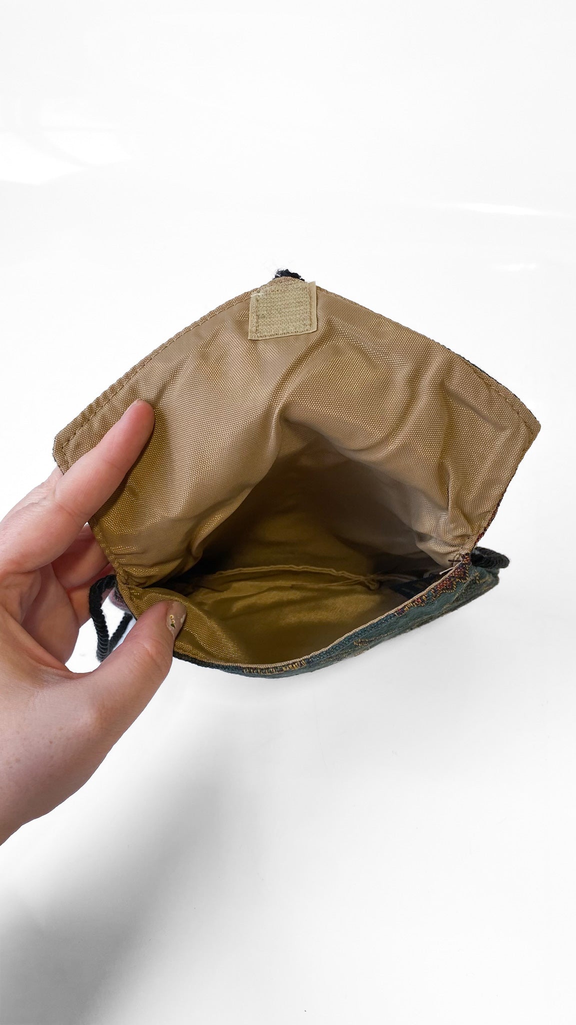 Hand holding a brown leather pouch with a white background
