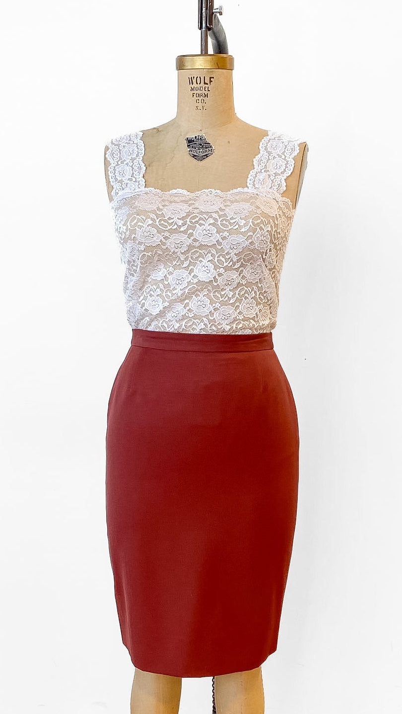 Mannequin wearing a white lace top and red pencil skirt on a wooden floor.