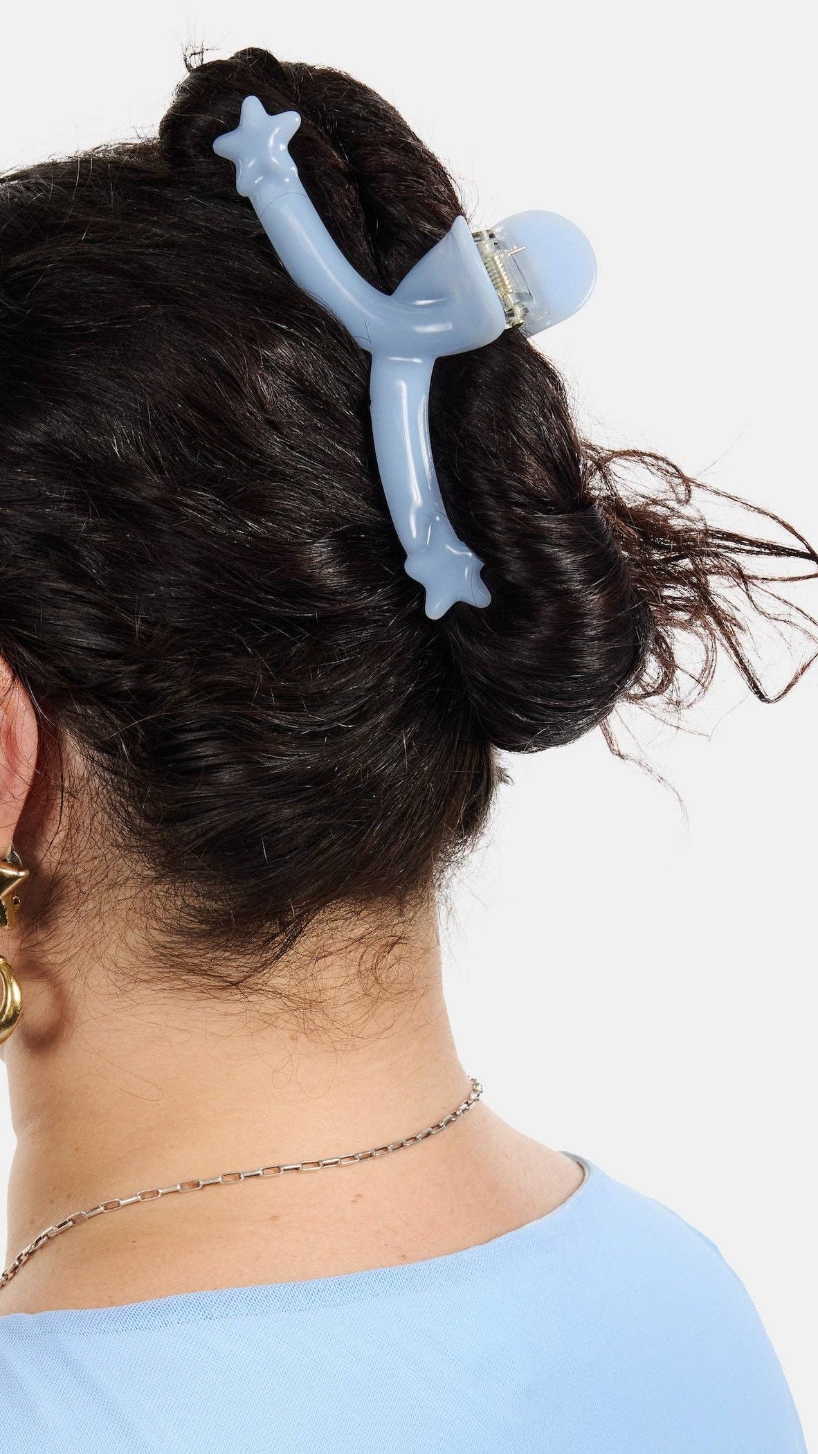 Person with a blue hair clip in their hair against a white background
