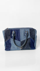 A blue patchwork denim tote bag with dual top handles and a top zipper closure, displayed on a clean white background.