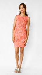 Woman wearing a pink dress with a white pattern on a white background