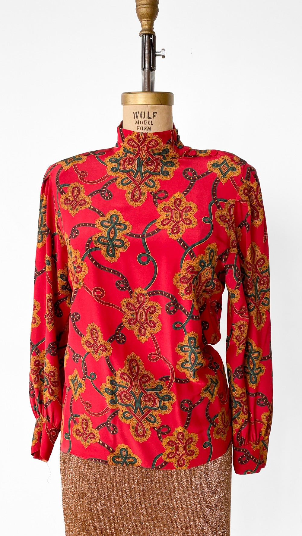Red floral blouse on a mannequin against a white background