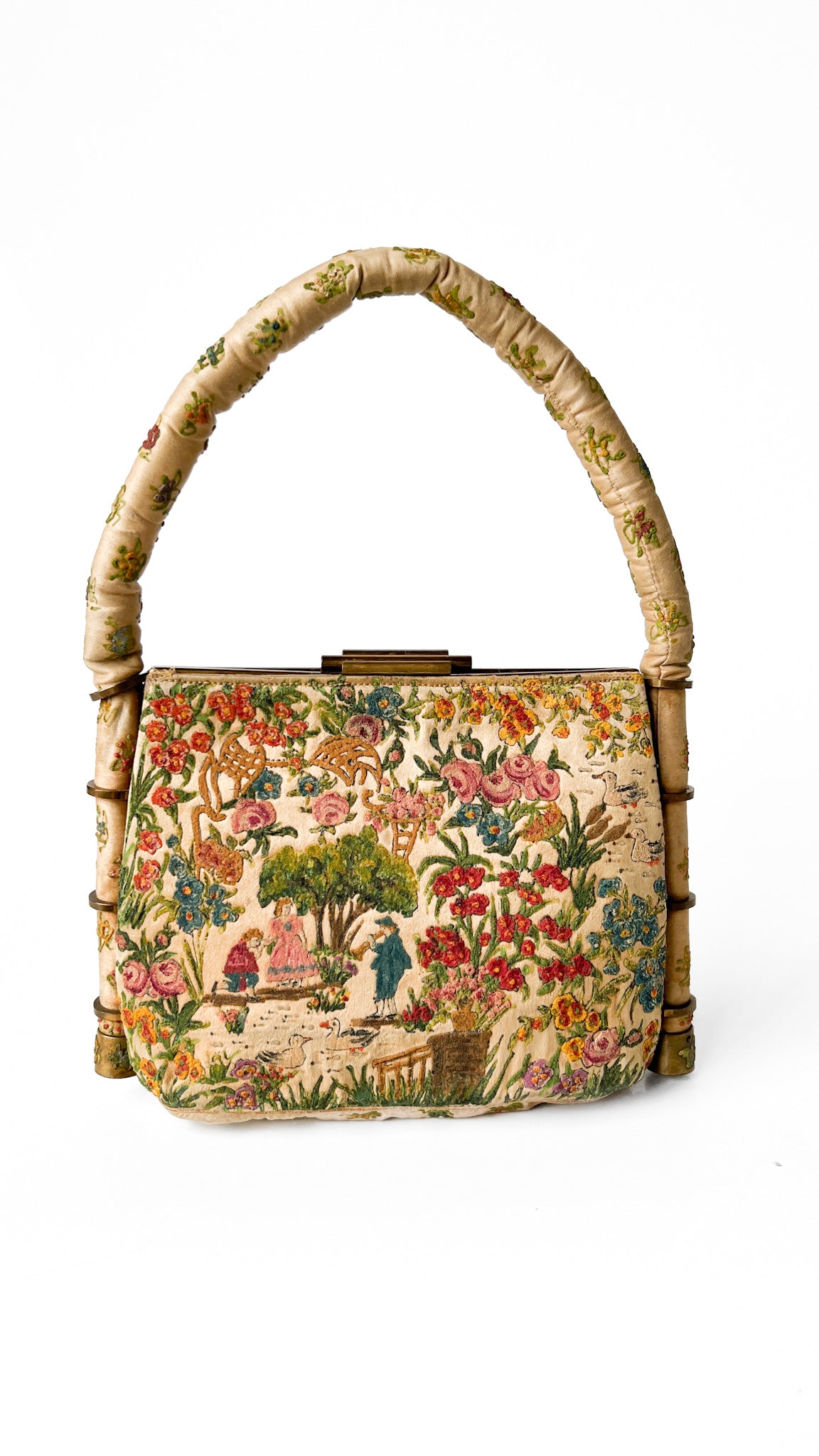 Vintage handbag with floral design and bamboo handle on a white background