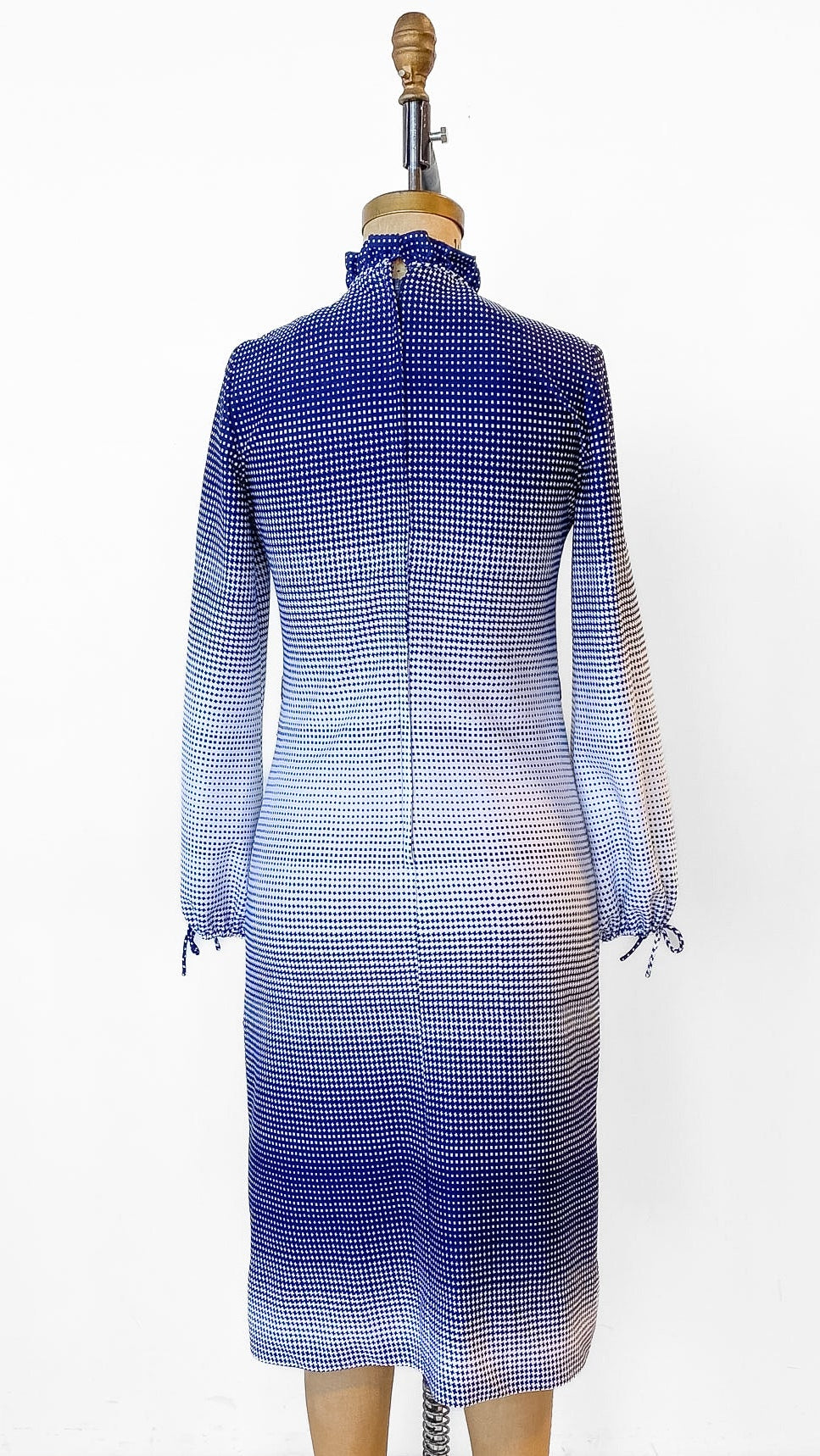 Mannequin wearing a blue and gray gradient dress on a wooden floor with a white background