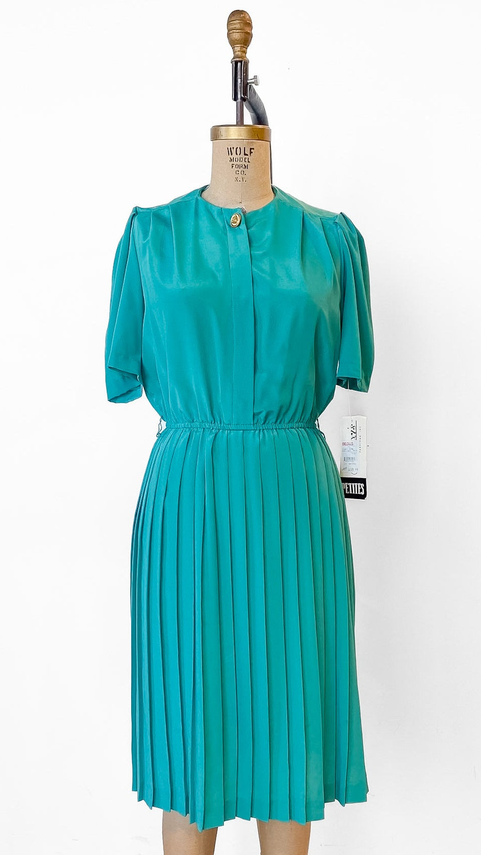 Teal dress on a mannequin against a white background