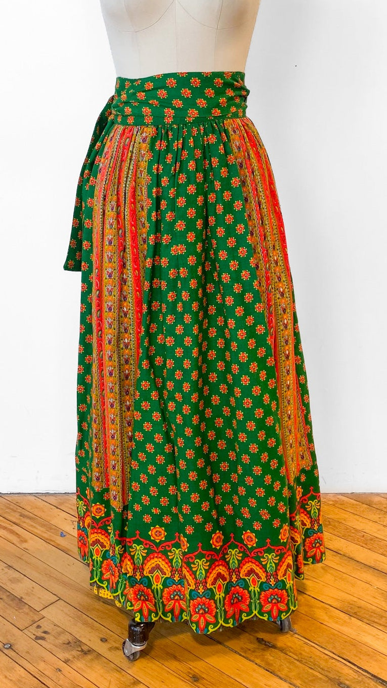 Mannequin wearing a green and orange patterned skirt on a wooden floor with white background