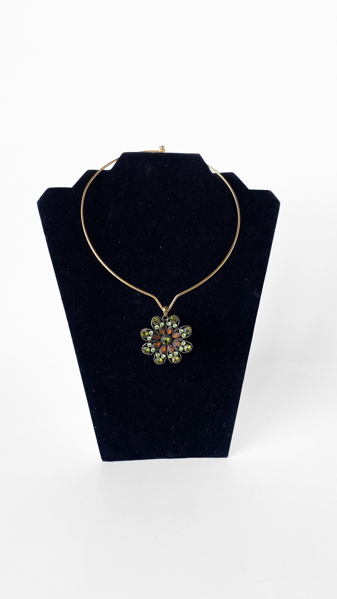 Necklace with a floral pendant on a black velvet stand against a white background