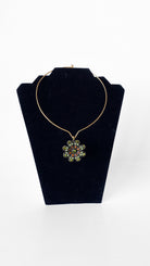 Necklace with a floral pendant on a black velvet stand against a white background