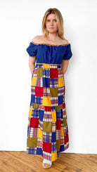 Woman wearing a colorful patchwork dress with a blue top against a white background
