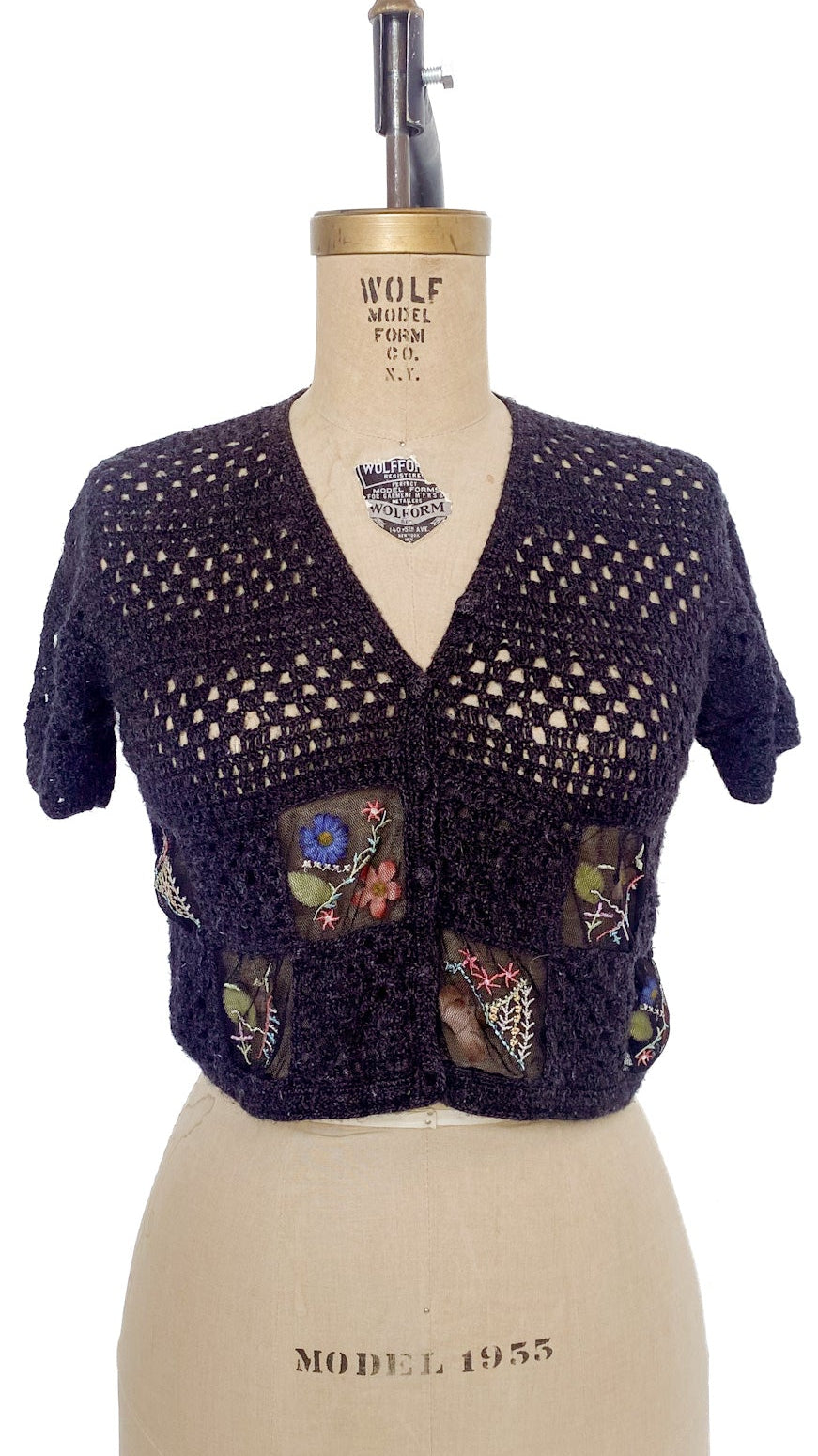 Knitted cardigan with colorful patches on a mannequin against a white background