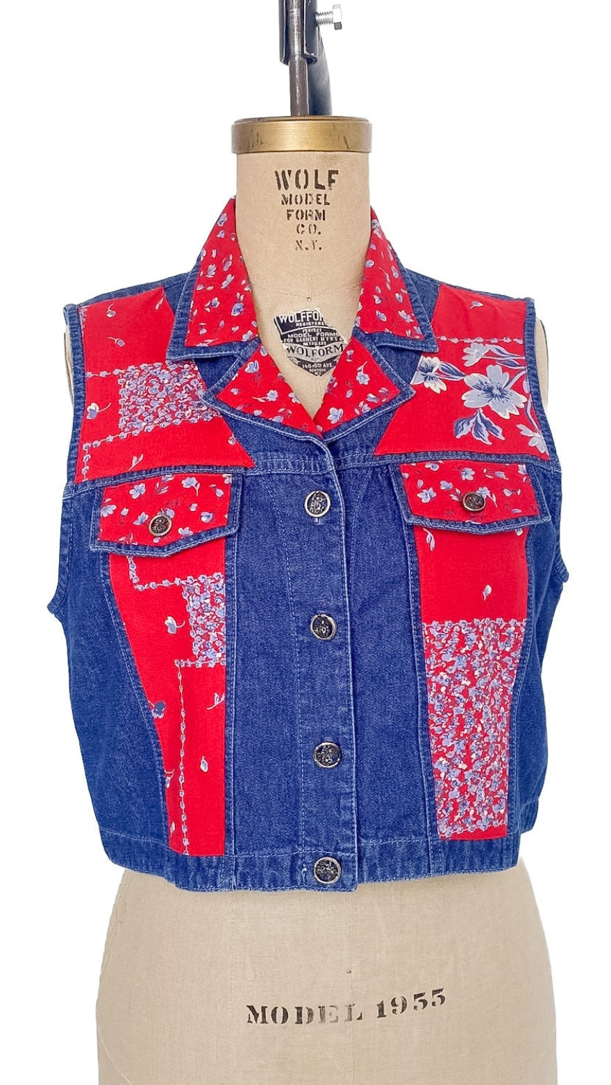 Patchwork vest with red and blue patterns on a mannequin against a white background