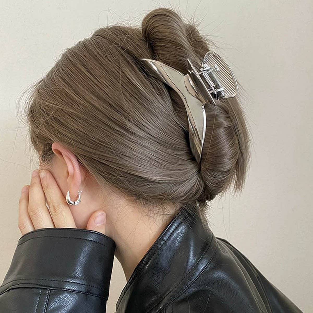 Person with a stylish hair clip in their bun against a neutral background