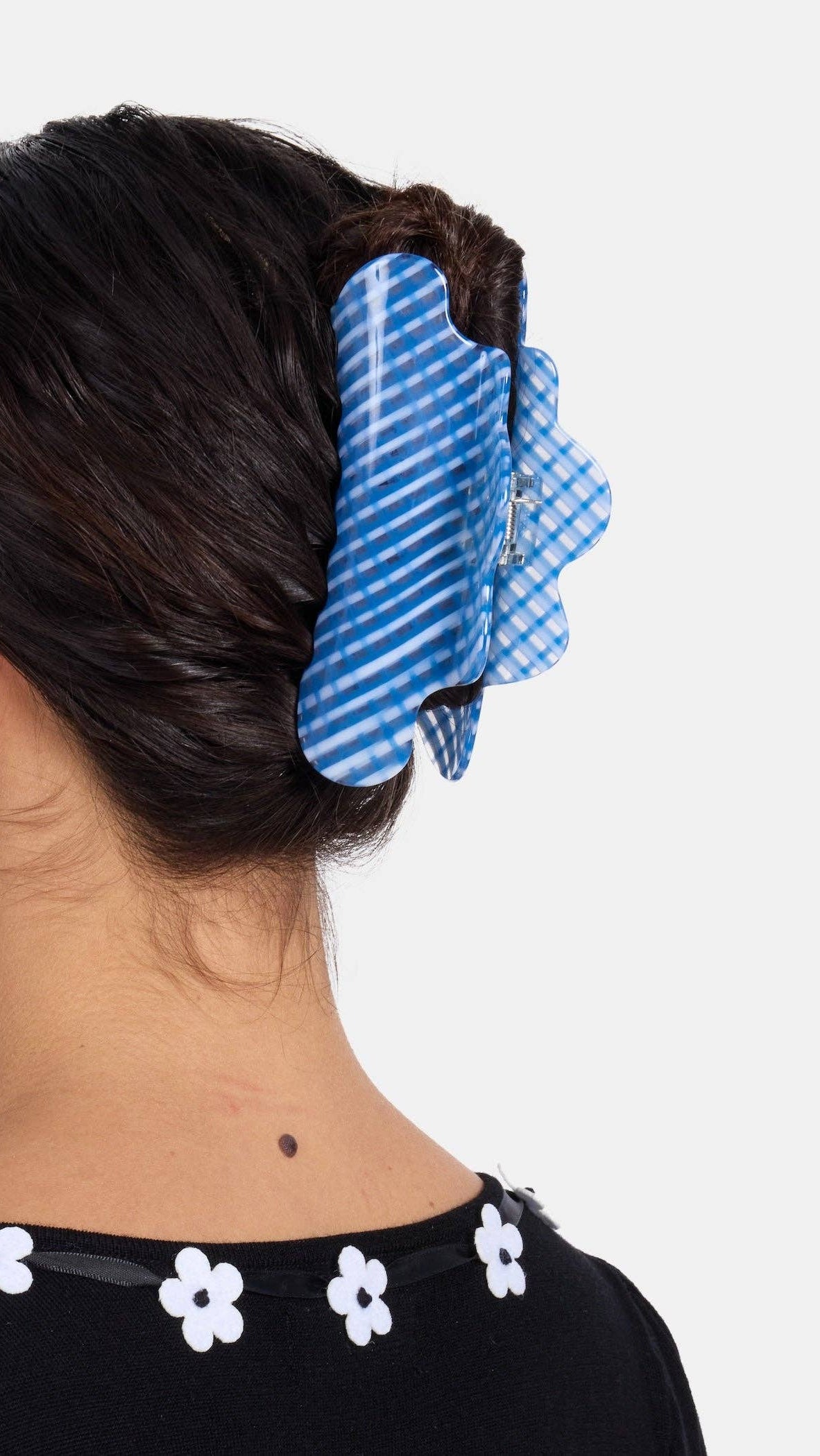 Person with hair tied up using a blue checkered hair tie on a white background