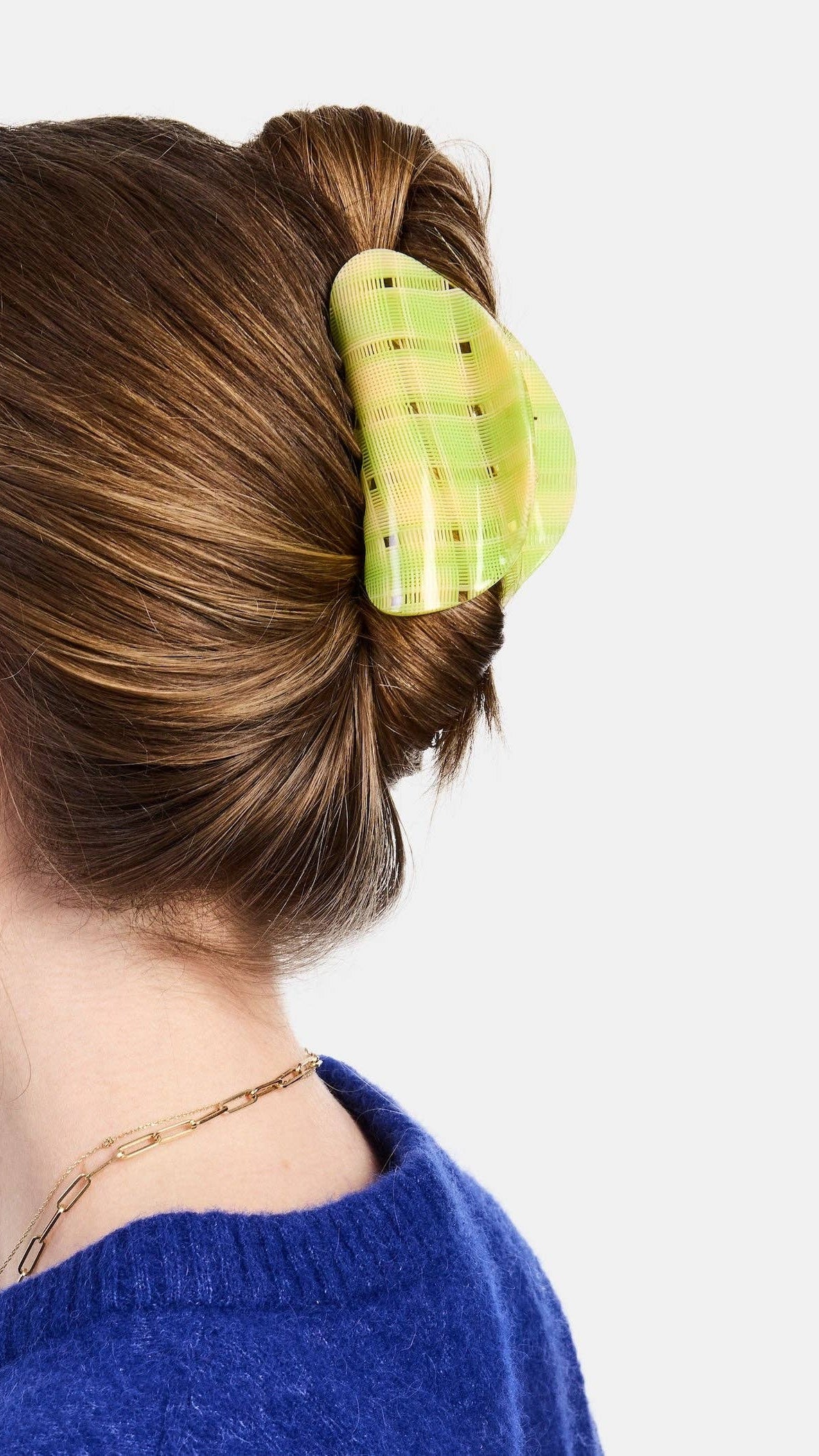 Person with hair in a bun using a green hair clip on a white background